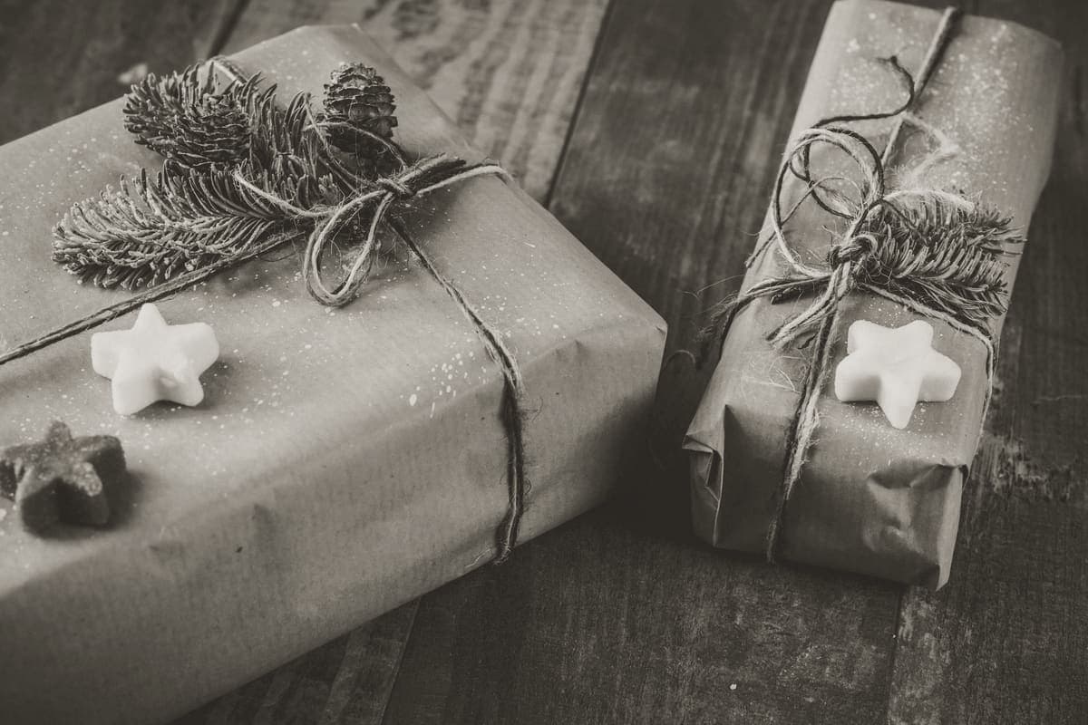 Two presents wrapped in brown kraft paper and twine on a wooden table